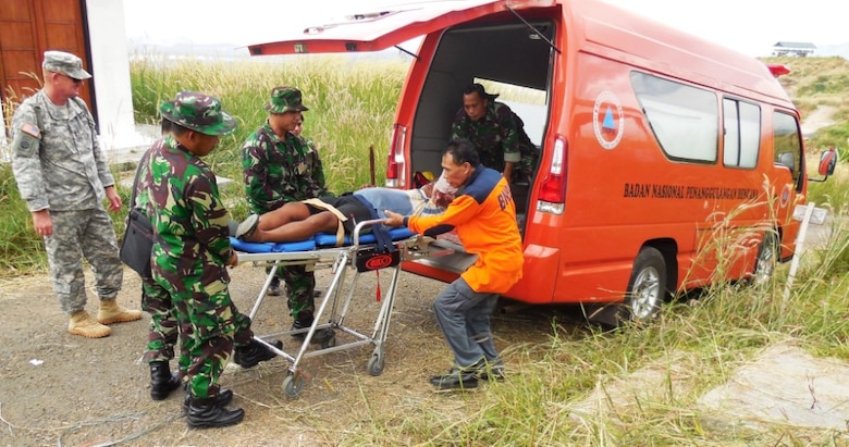 MSG Lonny Rogers (USARPAC) looks on as SRC-PB members offload an earthquake victim from an ambulance at the 2013 Indonesia Pacific Resilience Disaster Response Exercise & Exchange.