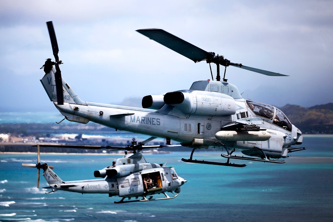 An AH-1W Super Cobra helicopter and UH-1Y Huey helicopter fly off the coast of Oahu, Hawaii, towards Marine Corps Air Station Kaneohe Bay, Hawaii, June 13, 2013.