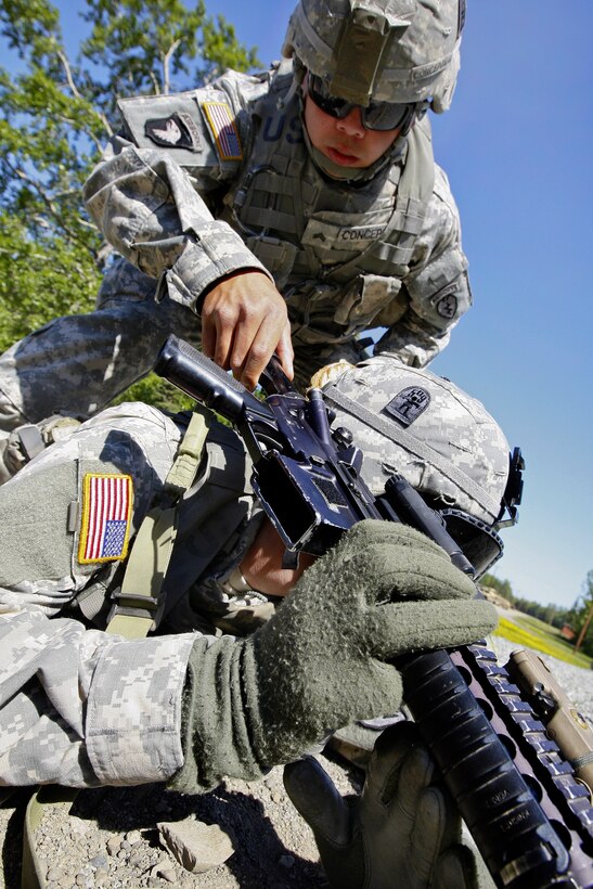 Army Sgt. Ryan Concepcion, standing, safety checks Army Pfc. James Sneed's M4 carbine before he departs the range after qaulifying during nuclear, biological and chemical training at the Small Arms Complex on Joint Base Elmendorf-Richardson, Alaska, June 17, 2013. Concepcion is assigned to Company F, and Sneed is assigned to Company B, 3rd Battalion, Airborne, 509th Infantry Regiment.