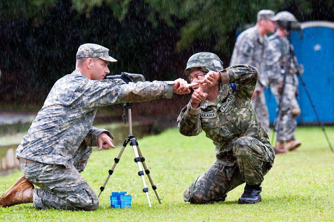 A U.S. paratrooper, left, explains to an Indonesian army paratrooper, right, how to sight through a sniper’s rifle scope during exercise Garuda Shield 2013 at 1st Kostrad headquarters in West Java, Indonesia, June 10, 2013.