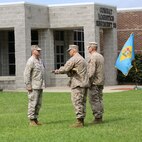 Newly appointed Command Master Chief Petty Officer Michael J. Roberts (center) receives a navy cutlass from Navy Capt. Cameron L. Waggoner (left), the commanding officer of 2nd Medical Battalion, 2nd Marine Logistics Group, aboard Camp Lejeune, N.C., June 18, 2013. The cutlass is passed from the off-going command master chief petty officer to the oncoming to symbolize the change of enlisted leadership. (U.S. Marine Corps photo by Lance Cpl. Shawn Valosin)