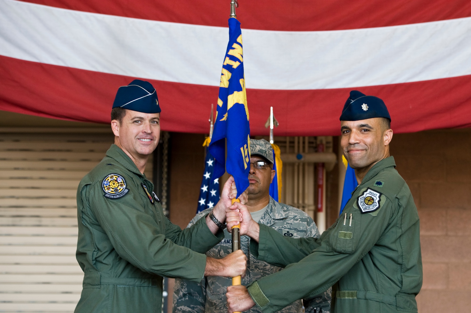 Lt. Col. Adrian Spain, U.S. Air Force Weapons School commandant, accepts the USAFWS guidon from Brig. Gen. Charles Moore, 57th Wing commander, during the USAFWS change of command ceremony at the F-22 Raptor hangar June 17, 2013, at Nellis Air Force Base, Nev. The USAFWS commandant commands 17 squadrons with more than 250 assigned instructors to provide graduate-level training in weapons and tactics employment to officers and enlisted of the combat air forces and mobility air forces. (U.S. Air Force photo by Airman 1st Class Christopher Tam)