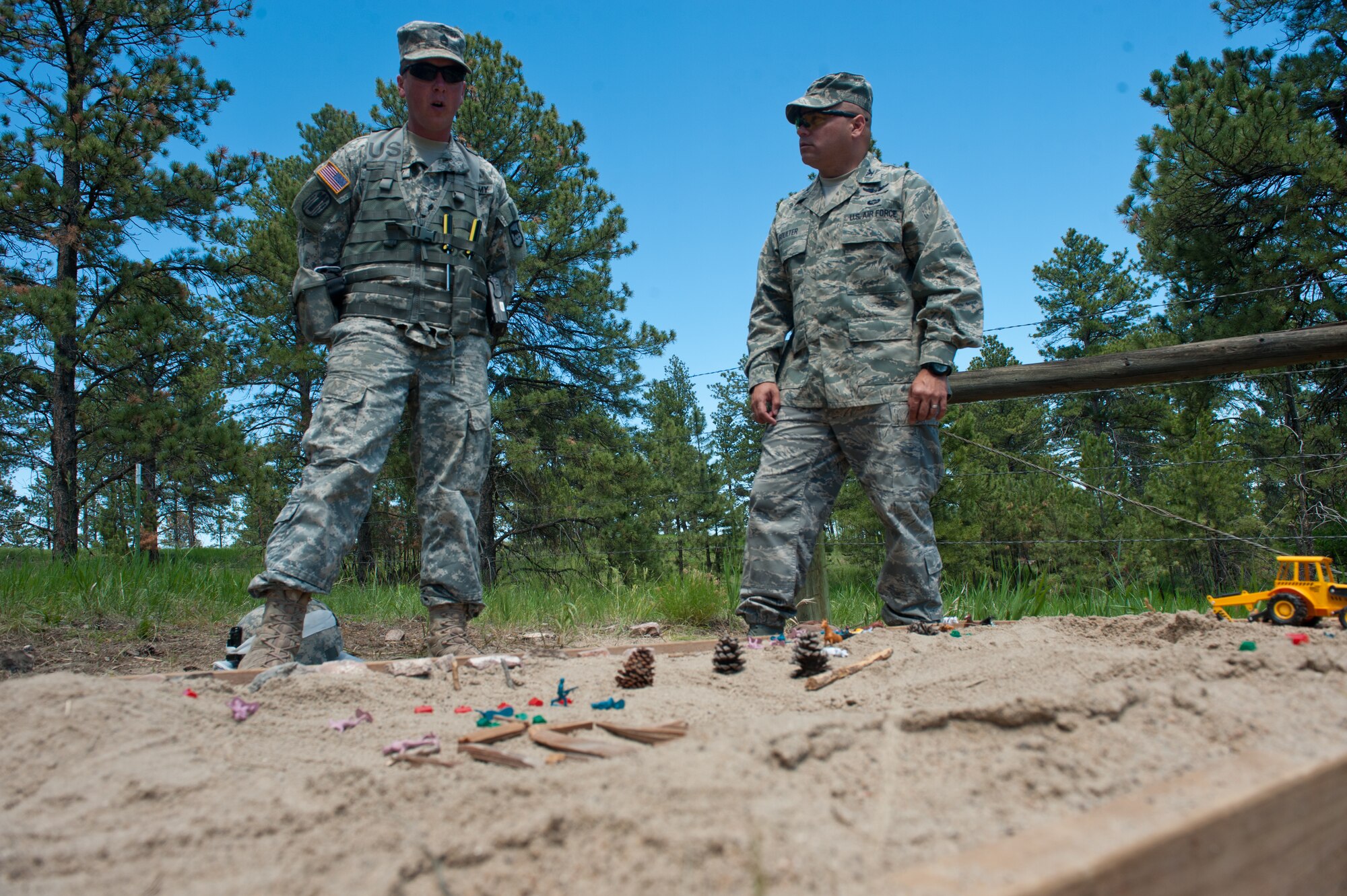 U.S. Army Staff Sgt. Dallas Vallery, South Dakota Army National Guard Joint Force Headquarters training instructor, explains a re-creation of the terrain around Camp Rapid to Col. Thomas Goulter Jr., 28th Mission Support Group commander, during the Golden Coyote exercise at Camp Rapid, S.D., June 18, 2013. The exercise challenged participants with combat simulations and scenarios to prepare them for possible real-world contingencies. (U.S. Air Force photo by Senior Airman Kate Maurer/Released)