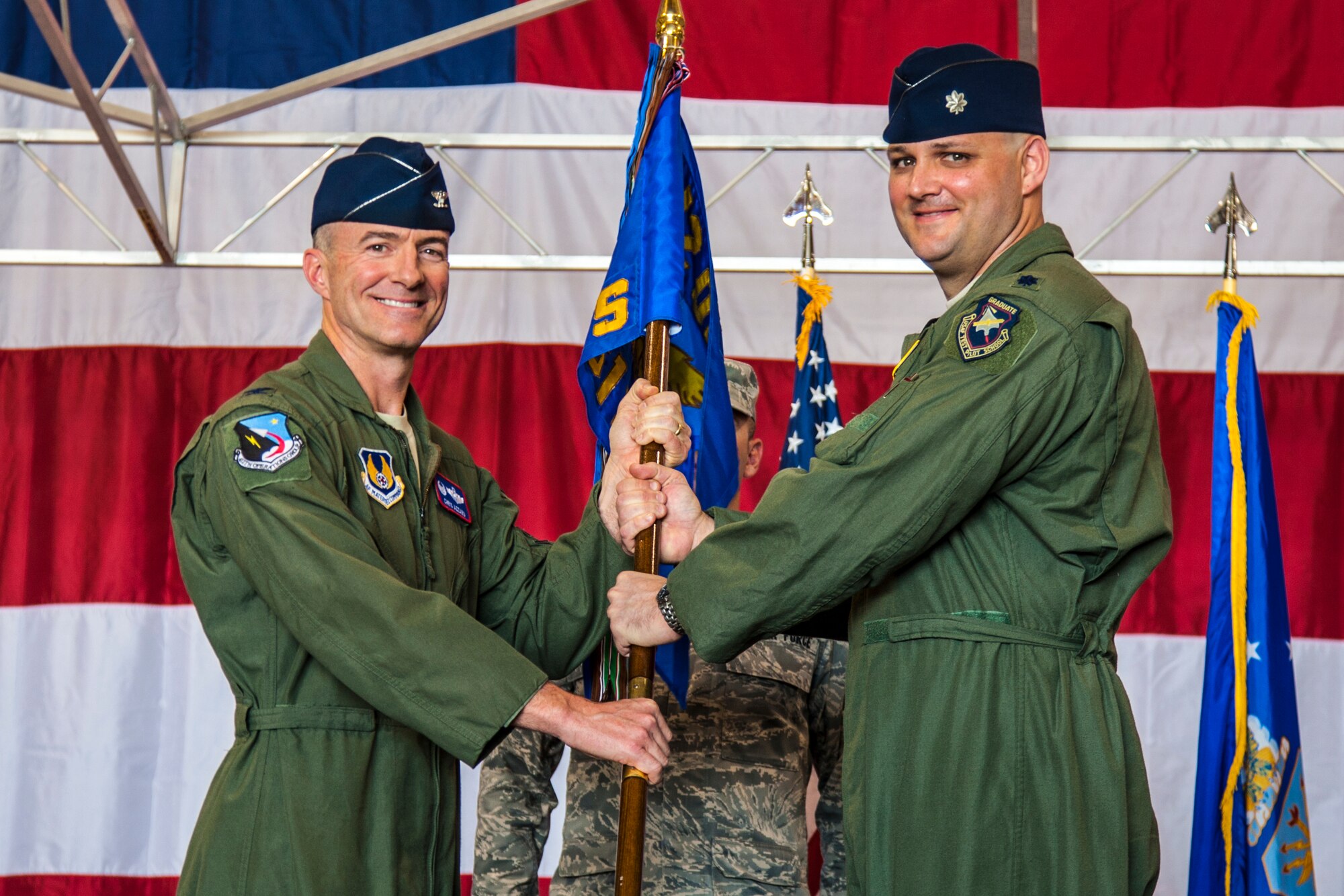 Col. Christopher Azzano, former 412th Operations Group commander, hands the 461st Flight Test Squadron guidon to Lt. Col. Andrew Allen during a change of command ceremony June 11. Allen assumed command of the squadron, which conducts developmental testing for the F-35 Joint Strike Fighter. (Courtesy photo by Darin Russell/Lockheed Martin)