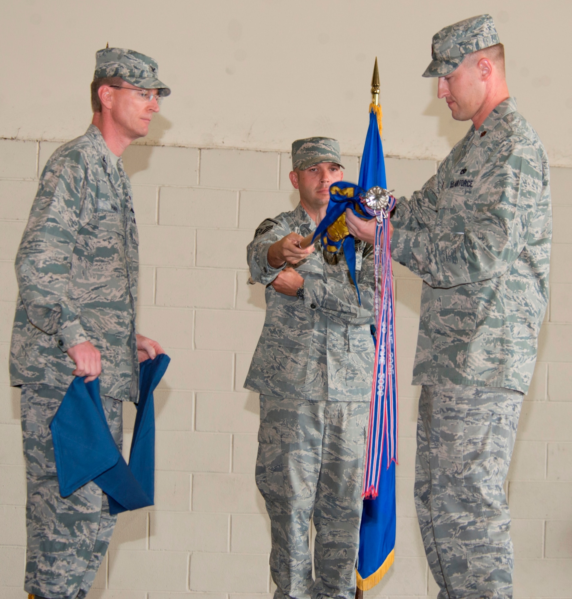 Col. Curtis Hafer, 325th Maintenance Group commander, Maj. Brady Poe, former 325th Maintenance Operations Squadron commander and Master Sgt. Edward Owsiany, 325th MOS first sergeant furl the squadron's guidon during an inactivation ceremony here June 20.(U.S. Air Force Photo by Lisa Norman)