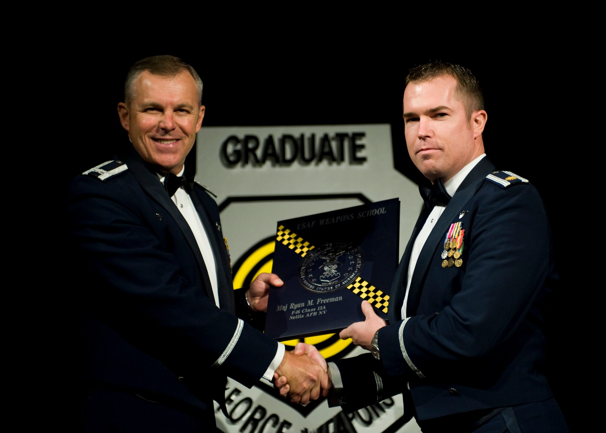 Maj. Ryan Freeman (right), an F-16 pilot with the 93rd Fight Squadron out of Homestead Air Reserve Base, Fla., receives his Weapons Instructor Course certificate from Col. Robert Garland, Air Force Weapons School commander, during the Air Force Weapons School’s Weapons Instructor Course graduation ceremony at Nellis Air Force Base, Nev., June 1. Freeman was one of only three reservists, in a class of 105 Airmen, to graduate the most recent round of classes. (U.S. Air Force photo/Airman 1st Class Jason Couillard)