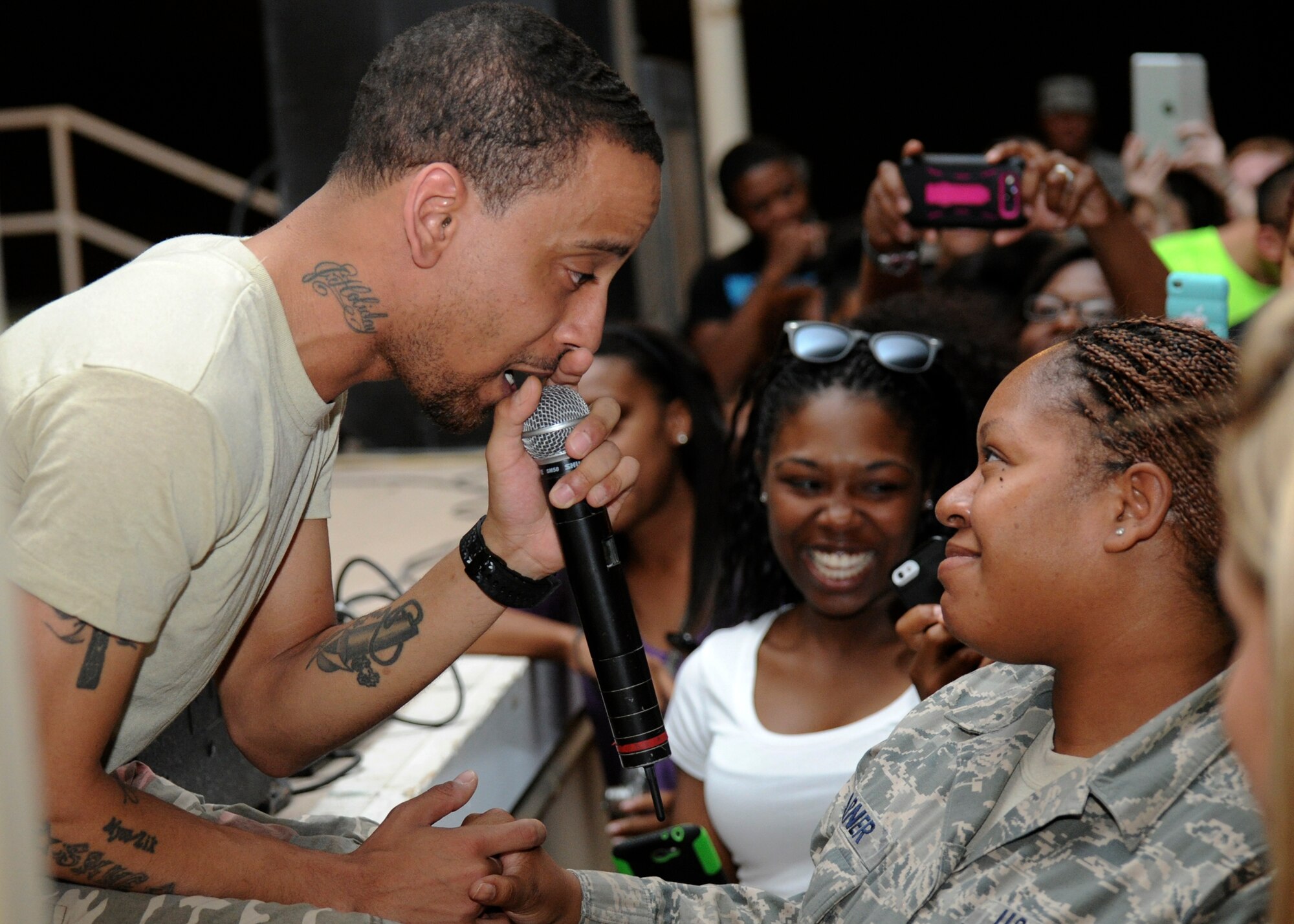 J. Holiday, a rhythm and blues vocalist serenades an Airman during a musical performance in Memorial Plaza at the 379th Air Expeditionary Wing in Southwest Asia, June 18, 2013. The performance was followed by a meet and greet where service members were given the opportunity to take photos with the artist. (U.S. Air Force photo/Senior Airman Bahja J. Jones)