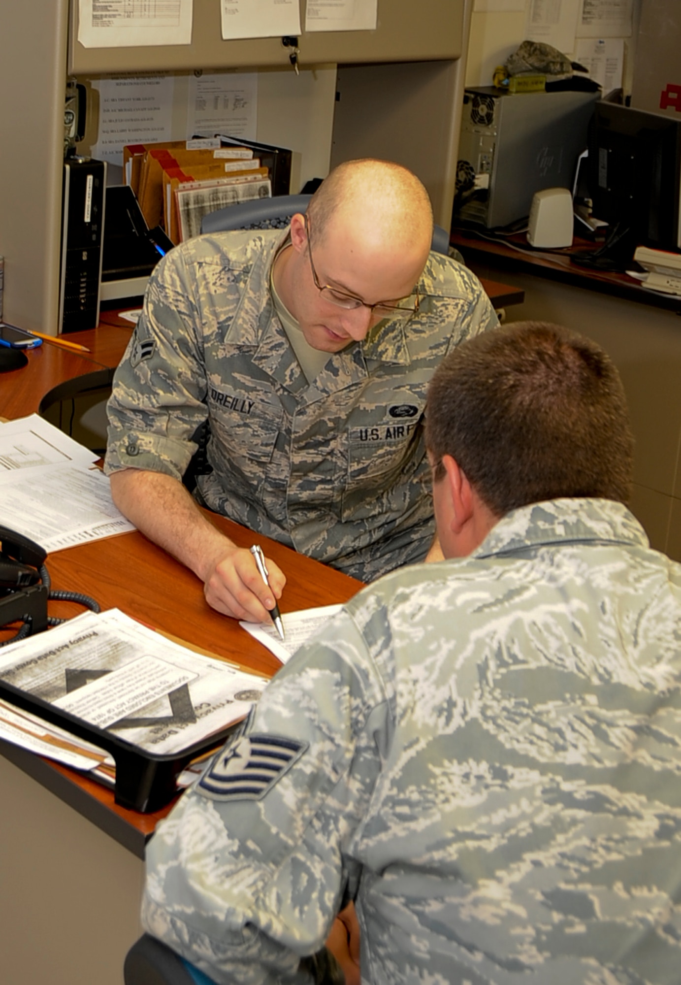 Airman 1st Class Jamison Orielly, a 2nd Force Support Squadron career development apprentice, reviews a customer's re-enlistment paperwork on Barksdale Air Force Base, La., June 10, 2013. Airmen at the 2nd FSS personnel section are experts in helping Airmen extend or re-enlist their service contracts. (U.S. Air Force photo/Staff Sgt. Jason McCasland)