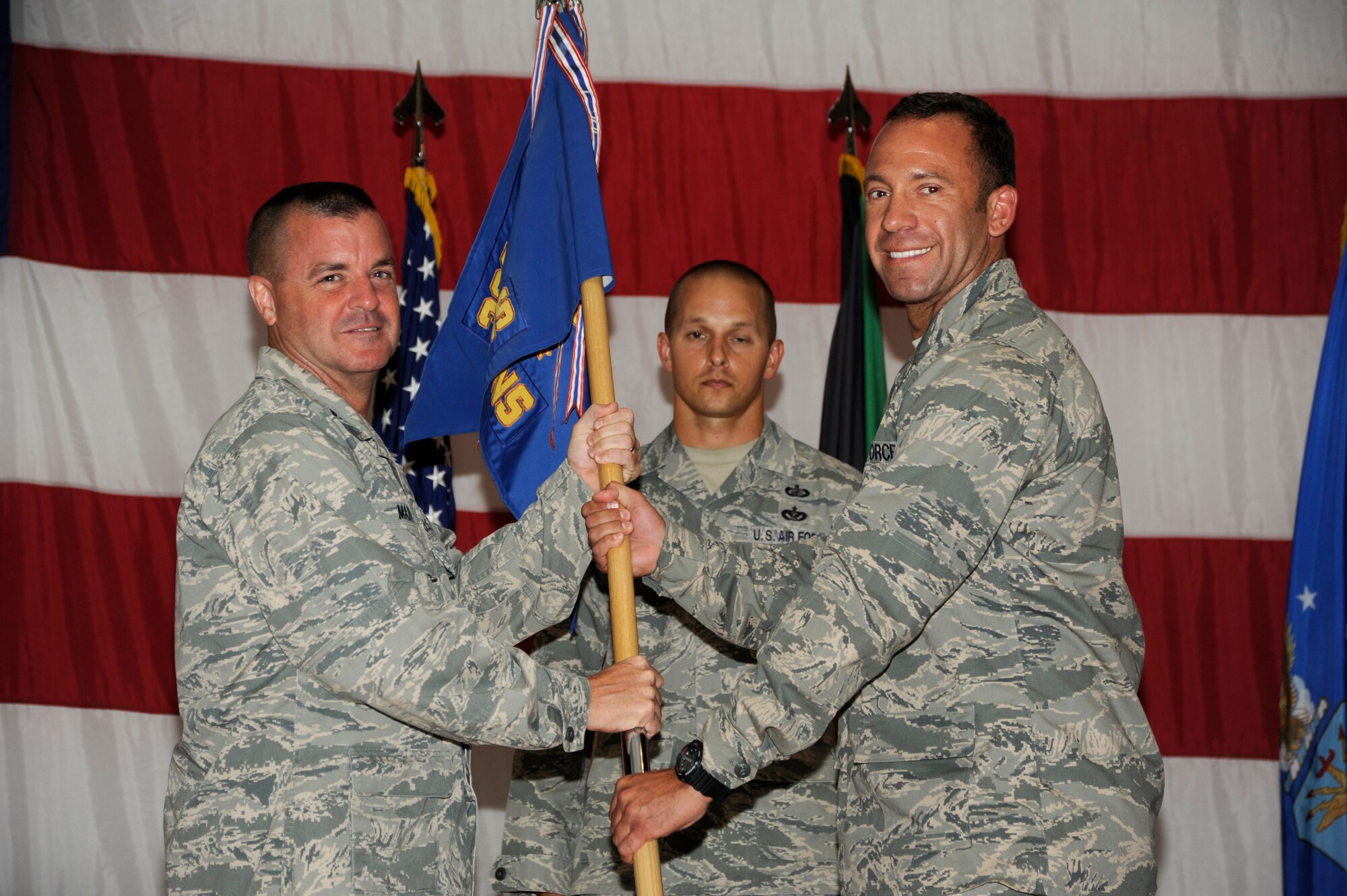 Colonel Joseph D. Martin, 386th Expeditionary Mission Support Group commander, left, passes the 386th Expeditionary Contracting Squadron guidon to Capt. Aaron H. Thomas during a change of command ceremony at an undisclosed location in Southwest Asia June 20, 2013.  Thomas assumed command of the 386th ECONS from Maj. Dawud K. Shillingford.  (U.S. Air Force photo by Master Sgt. Christopher A. Campbell)