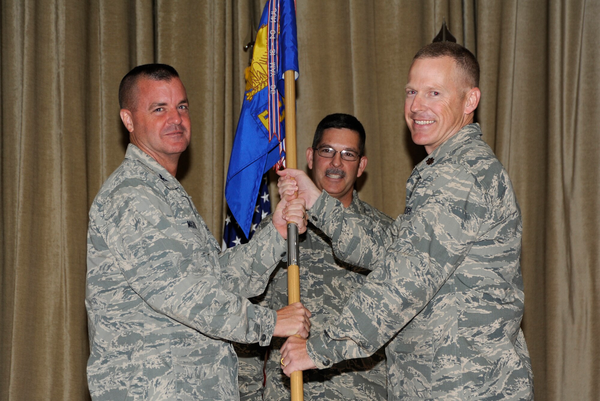 Colonel Joseph D. Martin, 386th Expeditionary Mission Support Group commander, left, passes the 386th Expeditionary Communications Squadron guidon to Maj. Robert A. Sides during a change of command ceremony at an undisclosed location in Southwest Asia June 20. Sides assumed command of the 386th ECS from Maj. Jeffrey R. Thompson (U.S. Air Force photo by Master Sgt. Christopher A. Campbell)
