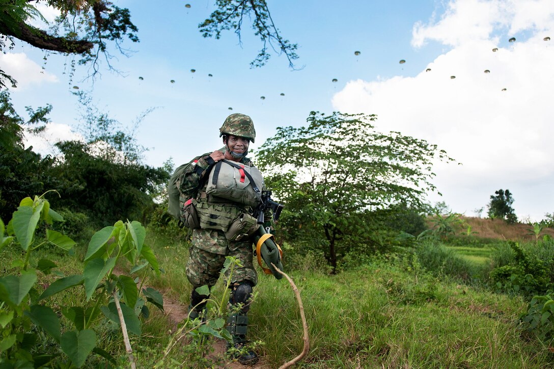 An Indonesian army paratrooper walks off a drop zone while more paratroopers descend behind him during a partnered mass-tactical airborne operation with U.S. paratroopers as part of exercise Garuda Shield 2013 bilateral training in West Java, Indonesia, June 18, 2013.