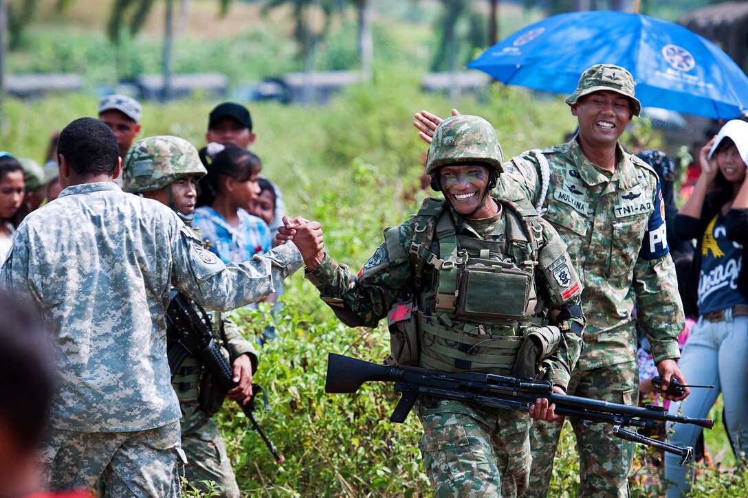 U.S. and Indonesian army paratroopers shake hands after completing a mass-tactical airborne operation and follow-on field training exercise during exercise Garuda Shield 2013 bilateral training in West Java, Indonesia, June 18, 2013.