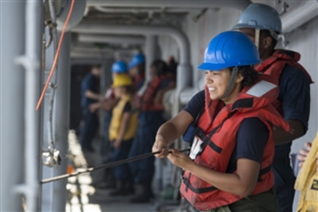 U.S. Navy Seaman Katurah Pearson heaves in a phone and distance line on the amphibious assault ship USS Kearsarge (LHD 3) during a replenishment-at-sea with the fleet replenishment oiler USNS Laramie (T-AO 203) in the Red Sea on June 14, 2013.  The Kearsarge Amphibious Ready Group, with the embarked 26th Marine Expeditionary Unit, is deployed to the 5th Fleet area of responsibility to conduct maritime security operations and theater security cooperation efforts.  