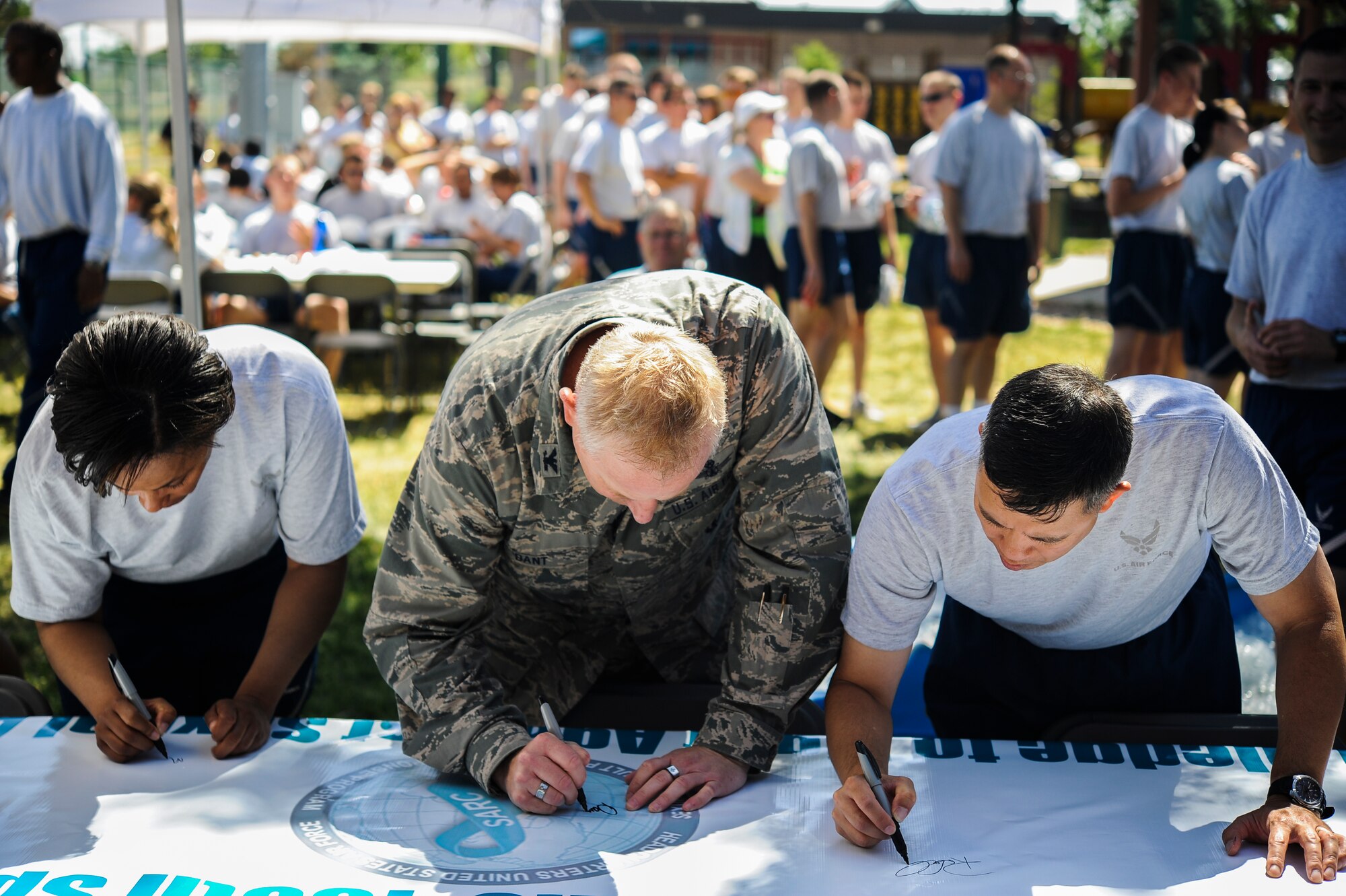Col. Dan Dant, 460th Space Wing commander, center; Col. Robert Uemura, 460th Mission Support Group commander, right; and Chief Master Sgt. Marilyn Savage, 460th Mission Support Group superintendent, left, sign the Sexual Assault Prevention and Response banner to pledge to fight against sexual assault in the military June 20, 2013, at the fitness center on Buckley Air Force Base, Colo. (U.S. Air Force photo by Staff Sgt. Paul Labbe/Released)