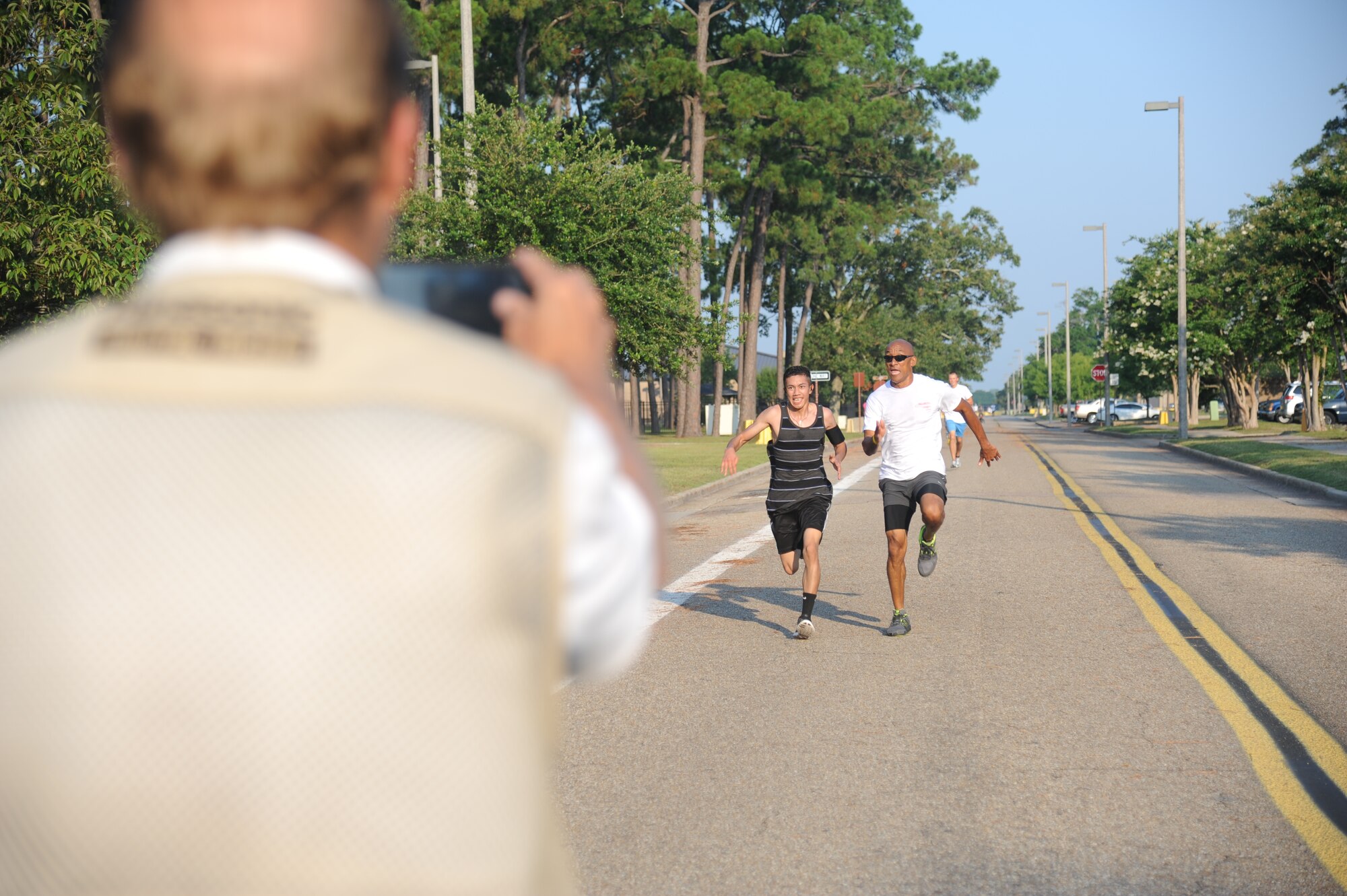 Doug Walker, WLOX reporter, takes a photo of Airman 1st Class Earl Pecson, 81st Diagnostic and Therapeutics Squadron, and Howard Chang, Computer Sciences Corporation, during a 5K run June 21, 2013, at Keesler Air Force Base, Miss., in support for Oklahoma tornado victims. More than 400 people pre-registered for the run and team Keesler raised more than $10,000 total to help aid in relief efforts.  (U.S. Air Force photo by Kemberly Groue)