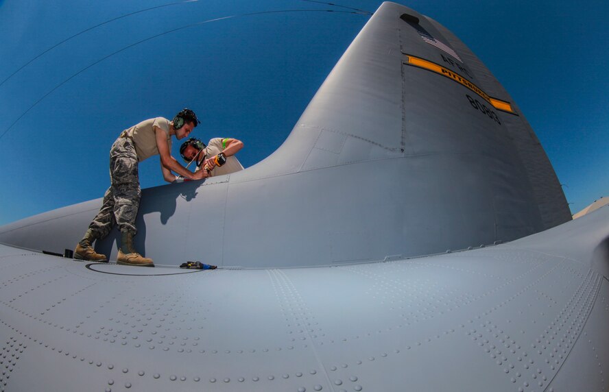 Staff Sgt. Jacob Pekelnicky and Tech. Sgt. Joseph Preston, 911th Maintenance Squadron avionics specialists, stand atop the fuselage of one of the unit’s equipped C-130 aircraft, while they replace a battery in the emergency locator transmitter June 19, 2013, at the Pittsburgh International Airport Air Reserve Station. The ELC battery is replaced every two years as part of technical order 1C-130A-6, which ensures that the transmitter will always send a signal to rescuers in the event of a mishap. (U.S. Air Force photo by Senior Airman Joshua J. Seybert)