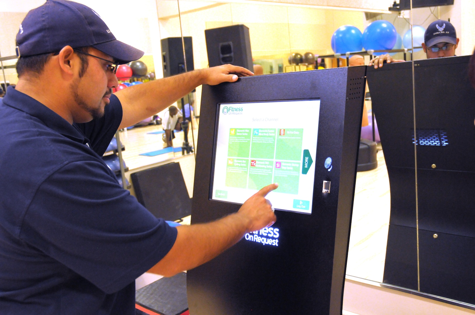 Rey Salinas, 902nd Force Support Squadron Rambler Fitness Center programs manager, demonstrates how to use the new Fitness on Request kiosk in the Rambler Fitness Center at Joint Base San Antonio-Randolph June 12, 2013. (U.S. Air Force Photo by A1C Alexandria Slade/ Released)
