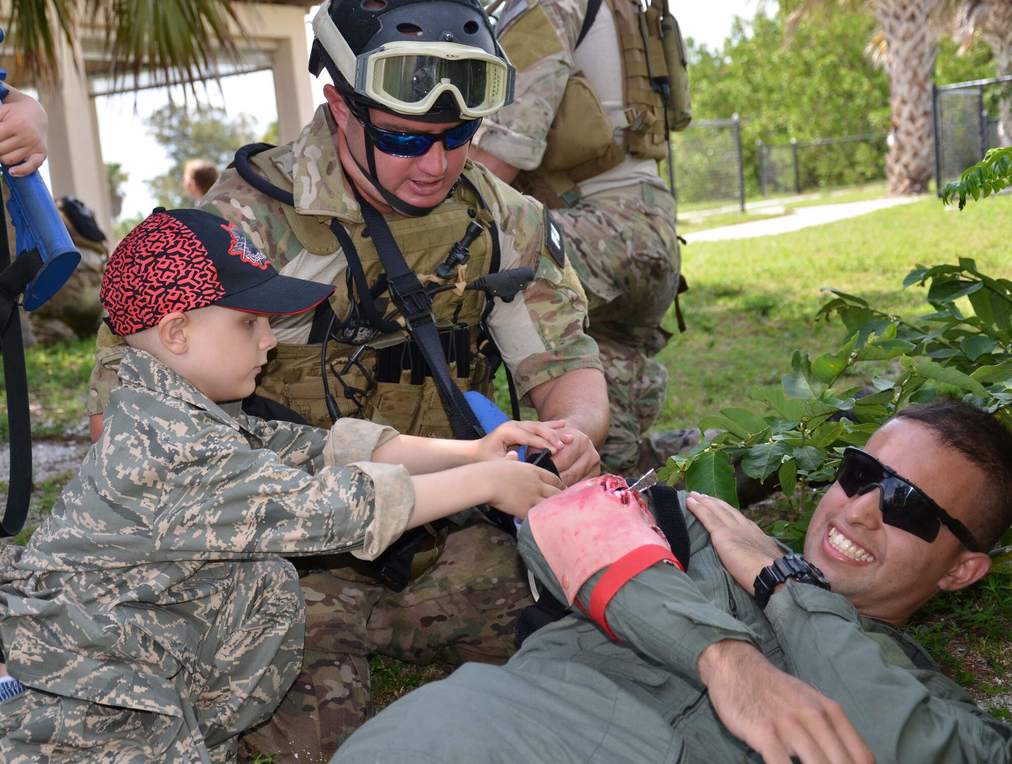 Staff Sgt. Louie Hause, 308th Rescue Squadron reserve pararescueman, is helped by Trevor Scheerer, 5, to medically treat a victim during a "rescue mission." The PJs formed two teams with Trevor and Finnian Gerts, 7, (not shown) leading the way, then boarded two awaiting Zodiac boats, making their rescue mission experience authentic. The missions consisted of traveling up the Banana River from the banks of the rescue squadron by boat about a quarter mile north to "rescue" and medically treat the injured pilots; all the while fighting off "enemy attacks". The boys and their families visited the 920th Rescue Wing, Cocoa Beach, Fla., to learn about combat search and rescue and meet the rescue professionals. The boys are both battling cancer and met while in treatment at Arnold Palmer Hospital in Orlando, Fla. They were treated to a day they would never forget - tours of both rescue aircraft, the King and HH-60G Pave Hawk helicopters, and then finished with a "rescue mission" hosted by the pararescuemen here. (U.S. Air Force photo/2nd Lt. Leslie Forshaw)