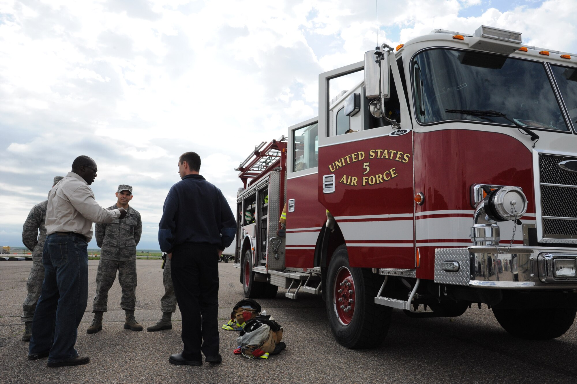 Devon Harris, a retired Jamaican army captain and member of the first Jamaican bobsled team, talks with firemen from the 341st Civil Engineer Squadron on June 11 about some of the tools they use on Malmstrom Air Force Base.  He learned about the instruments and tools used on fire trucks and some of the special abilities of the vehicles that help the firemen accomplish their mission. (U.S. Air Force photo/Airman 1st Class Collin Schmidt)