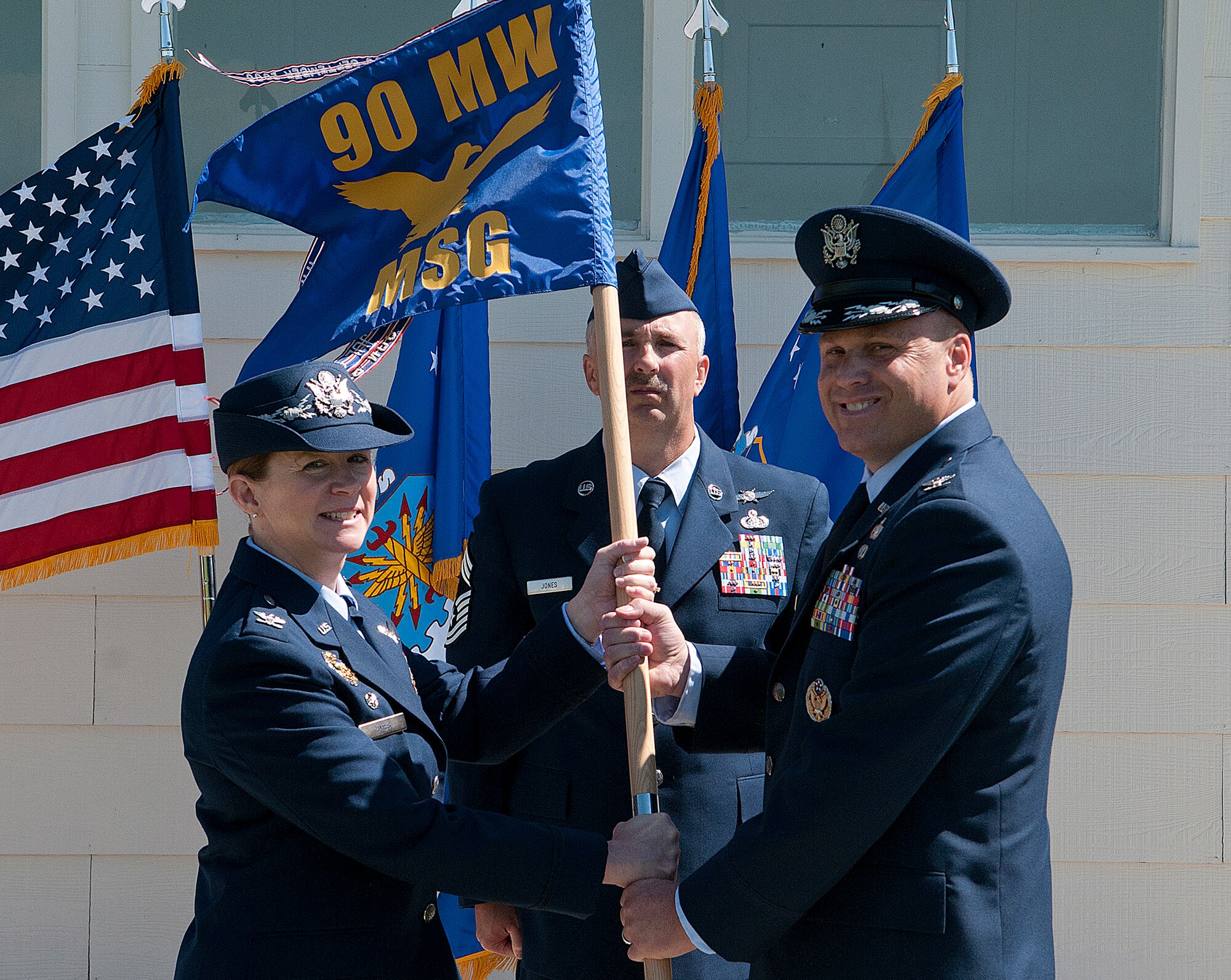 Col. Tracey Hayes, 90th Missile Wing commander, presents Col. Travis Condon with the 90th Mission Support Group guidon as he assumes command of the unit during a ceremony on F. E. Warren Air Force Base June 18, 2013. Chief Master Sgt. Ernest Jones, 90th MSG superintendent, looks on. (U. S. Air Force photo by R.J. Oriez)