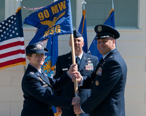 Col. Tracey Hayes, 90th Missile Wing commander, presents Col. Travis Condon with the 90th Mission Support Group guidon as he assumes command of the unit during a ceremony on F. E. Warren Air Force Base June 18, 2013. Chief Master Sgt. Ernest Jones, 90th MSG superintendent, looks on. (U. S. Air Force photo by R.J. Oriez)