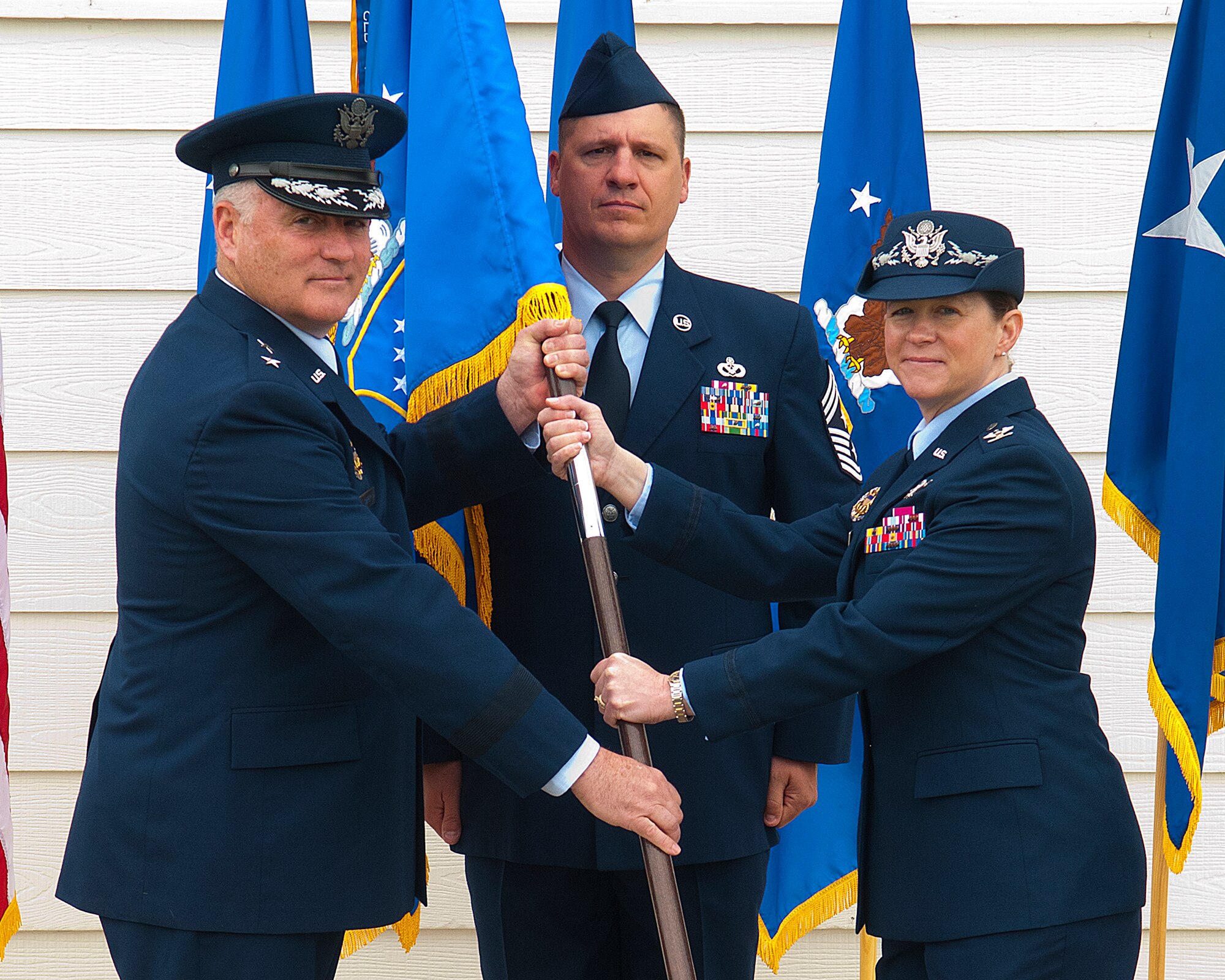 Maj. Gen. Michael Carey, 20th Air Force commander, passes the 90th Missile Wing flag to Col. Tracey Hayes as she assumes command of the 90th MW during a ceremony on F. E. Warren Air Force Base June 17, 2013. Chief Master Sgt. Michael Garrou, 90th MW command chief stands by to take the flag from Hayes. (U.S. Air Force photo by R.J. Oriez)