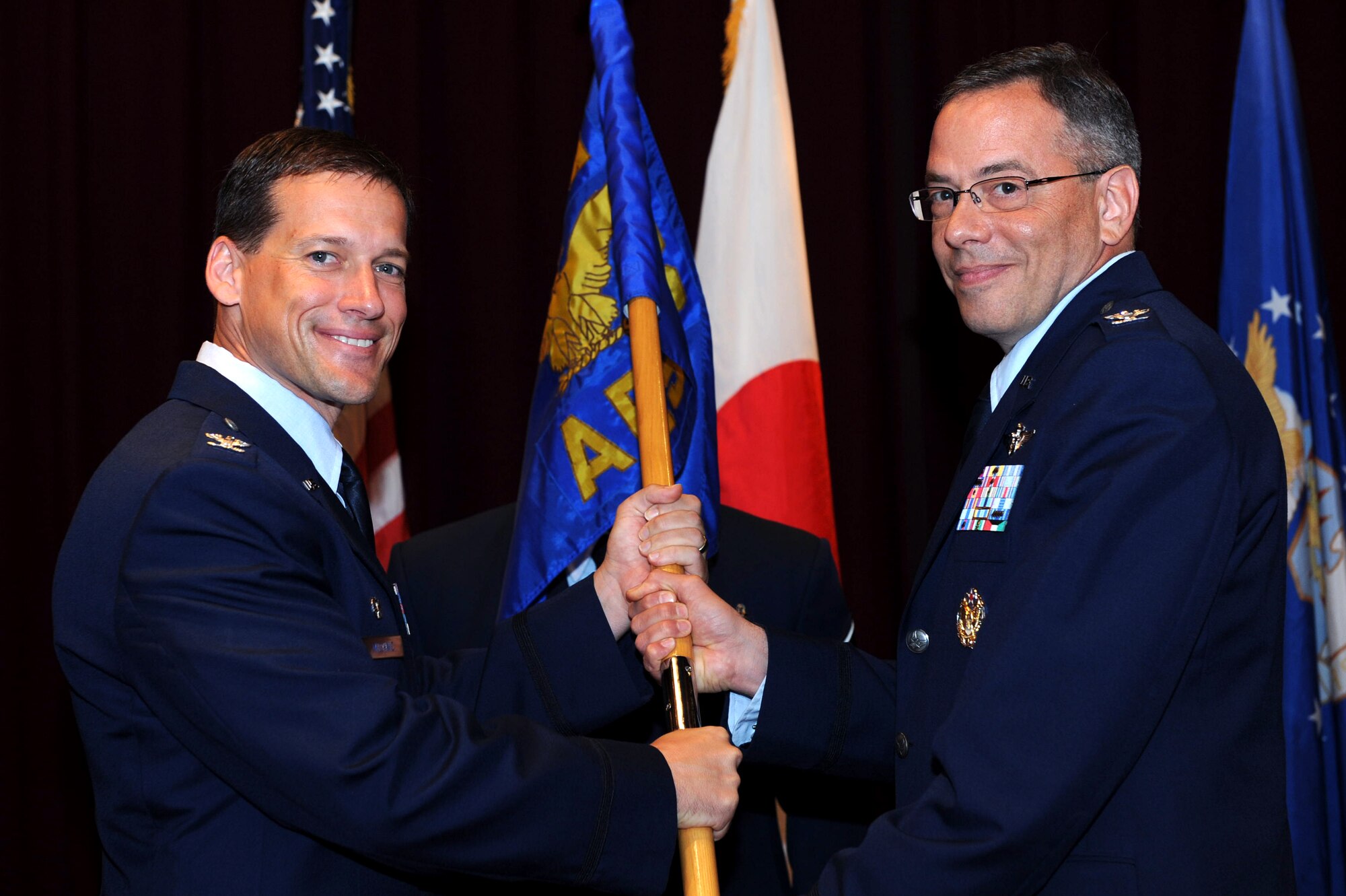 U.S. Air Force Col. Peter Milohnic, 18th Operations Group commander, passes the 18th Aeromedical Evacuation Squadron guidon to Col. Dale Grey, 18th AES commander, at the change of command ceremony on Kadena Air Base, Japan, June 21, 2013. Grey has been stationed within the Pacific area of operations twice and recently completed an assignment as senior executive fellow of the Medical Force Development section at the Pentagon, Washington, D.C. (U.S. Air Force photo by Airman 1st Class Hailey R. Davis/Released)  