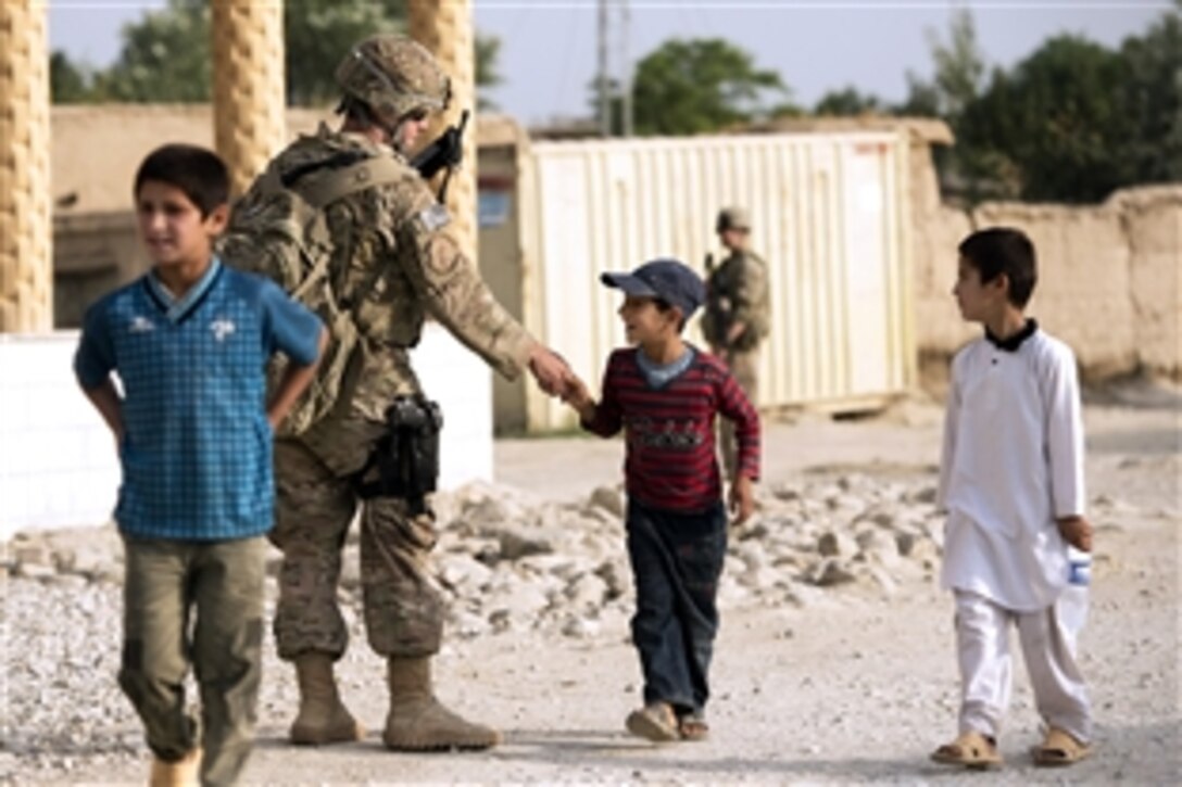 U.S. Air Force Staff Sgt. Michael Sweeney exchanges greetings with an Afghan boy while providing security in the town of Saka near Bagram Airfield in Parwan province, Afghanistan, June 13, 2013. Sweeney is assigned to the 455th Expeditionary Security Forces Group. U.S. airmen from that unit and the 577th Expeditionary Prime Base Engineer Emergency Force Squadron worked together to rebuild a road connecting Saka and Payan Janqadam.