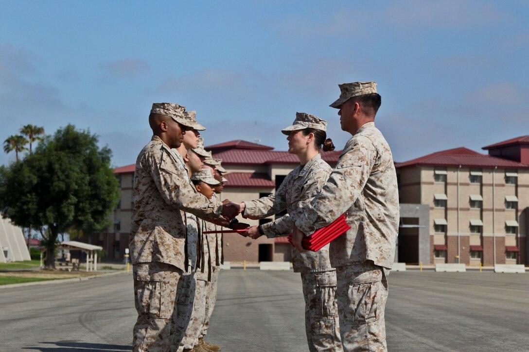 Sergeant Matthew Page, disbursing agent, receives a Navy and Marine Corps Achievement Medal from Capt. Janine Mills, adjutant, both with Command Element, 15th Marine Expeditionary Unit, during an awards ceremony held on the Camp Del Mar Parade Deck on Camp Pendleton, Calif., June 17. Page received the award for superior achievement in his duties as a disbursing agent and for the support he provided to MEU operations ashore. Page, 21, is from Hong Kong. (U.S. Marine Corps photo by Cpl. Emmanuel Ramos/Released) 