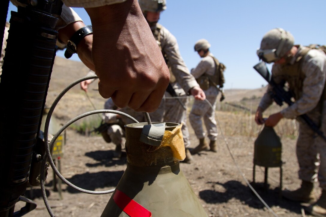 Marines serving with Bravo Company, 1st Combat Engineer Battalion, attach a detonation cord to a 40-pound shape charge at Range 108 here, June 19, 2013. The company conducted a demolition training range where Marines learned about the capabilities of various explosives such as dynamite, TNT, shape charges and C4. The charges are used by engineers to destroy heavily armored vehicles, defensive obstacles and bridges.