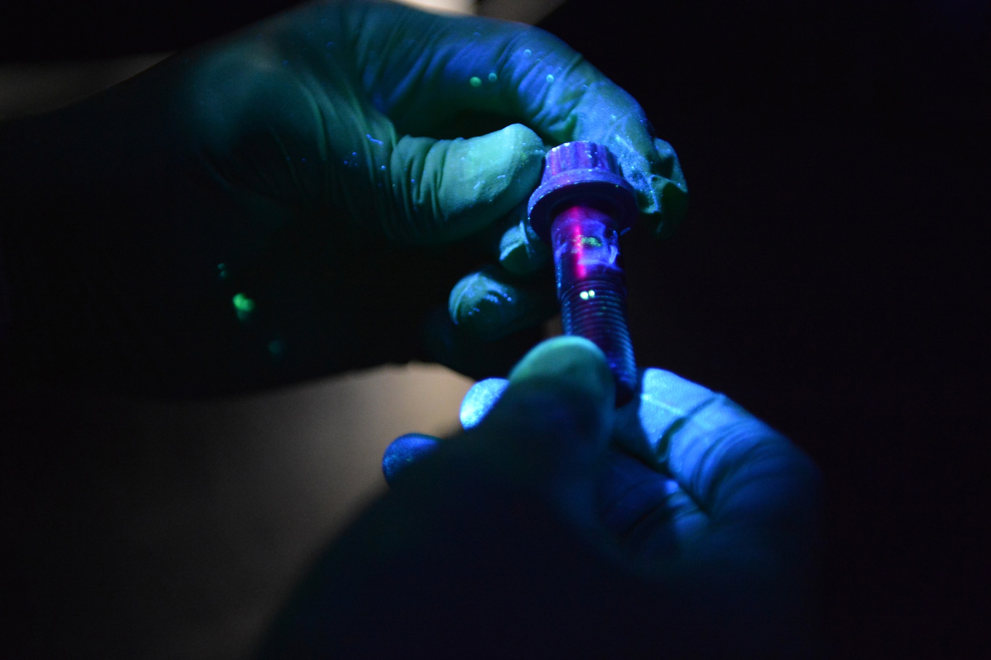 Airman 1st Class Garee Gregory, 62nd Maintenance Squadron nondestructive inspection technician, examines a bolt used on a C-17 Globemaster III aircraft braking system under a black light during a penetrant inspection June 18, 2013 at Joint Base Lewis-McChord, Wash. A penetrant inspection is an eight step process that requires a black light to determine defects within hardware or equipment being inspected. (U.S. Air Force photo/Airman 1st Class Jacob Jimenez) 