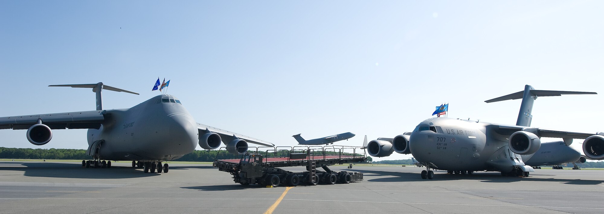 A C-5M Super Galaxy, (left) along with a cargo transport vehicle known as a K-loader and C-17A Globemaster III sit on the flightline at Dover Air Force Base, Del. on June 20th, 2013 prior to the 436th Maintenance Group Change of Command ceremony here. Also captured is another C-5M taking off in the background. Dover AFB is home to the Dept. of Defenses busiest aerial port and, under the 436th Airlift Wing, operates a mixed fleet of C-5M and C-17 airlift aircraft. (U.S. Air Force photo/Greg L. Davis)