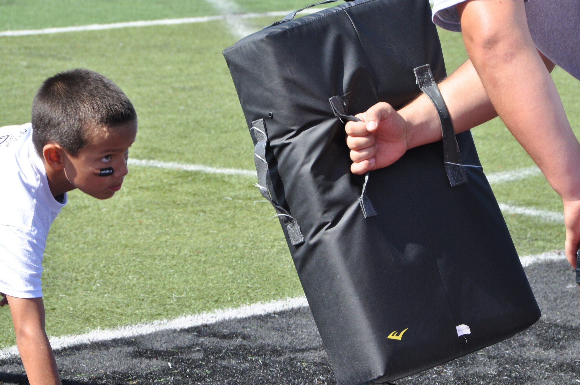 A child prepares to hit a pad held by his coach during a football pro-camp Saturday at Palo Alto. The variety of drills and training administered during the camp helped children hone their skills. (U.S. Air Force photo/Staff Sgt. Christopher Carranza)