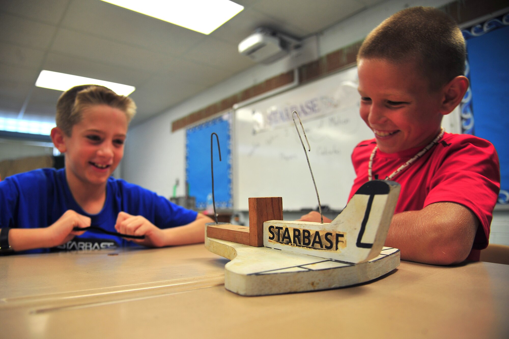 Children laugh as they think about how to secure an egg to a wooden aircraft while attending the Science and Technology Academies Reinforcing Basic Aviation and Space Exploration program at Meadow Lane Elementary School in Goldsboro, N.C., June 18, 2013. Children learned about math and science through interactive demonstrations and with help from local teachers and members of the 336th Fighter Squadron stationed at Seymour Johnson Air Force Base, N.C. (U.S. Air Force photo by Senior Airman Aubrey White/Released)