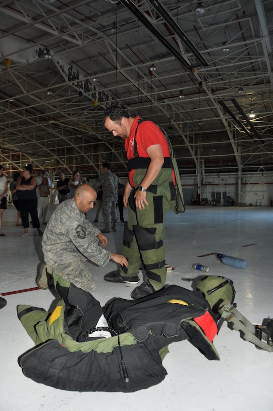 A member of Leadership Niagara dons EOD protective gear with the help of Master Sgt. Daniel Gervais during a tour here, June 20, 2013. (U.S. Air Force photo by Staff Sgt. Stephanie Clark) 