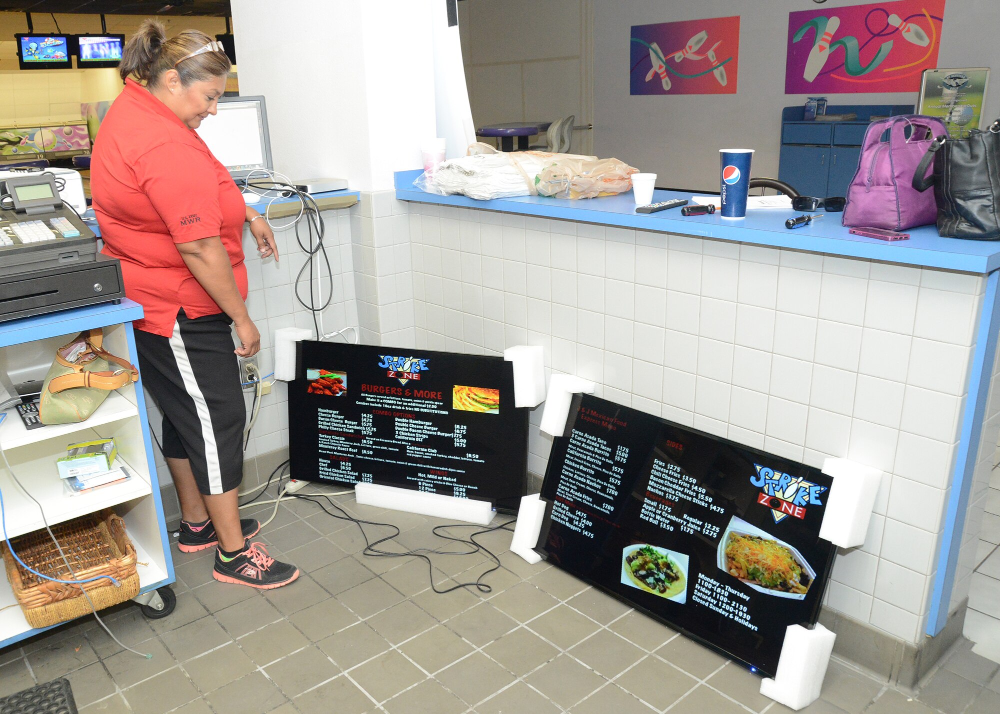 Jessie Salcedo, a contractor, looks at two electronic menus for the newly reopened Strike Zone snack bar at the Edwards Bowling Center. The eatery opens this week. (U.S. Air Force photo by Kenji Thuloweit)