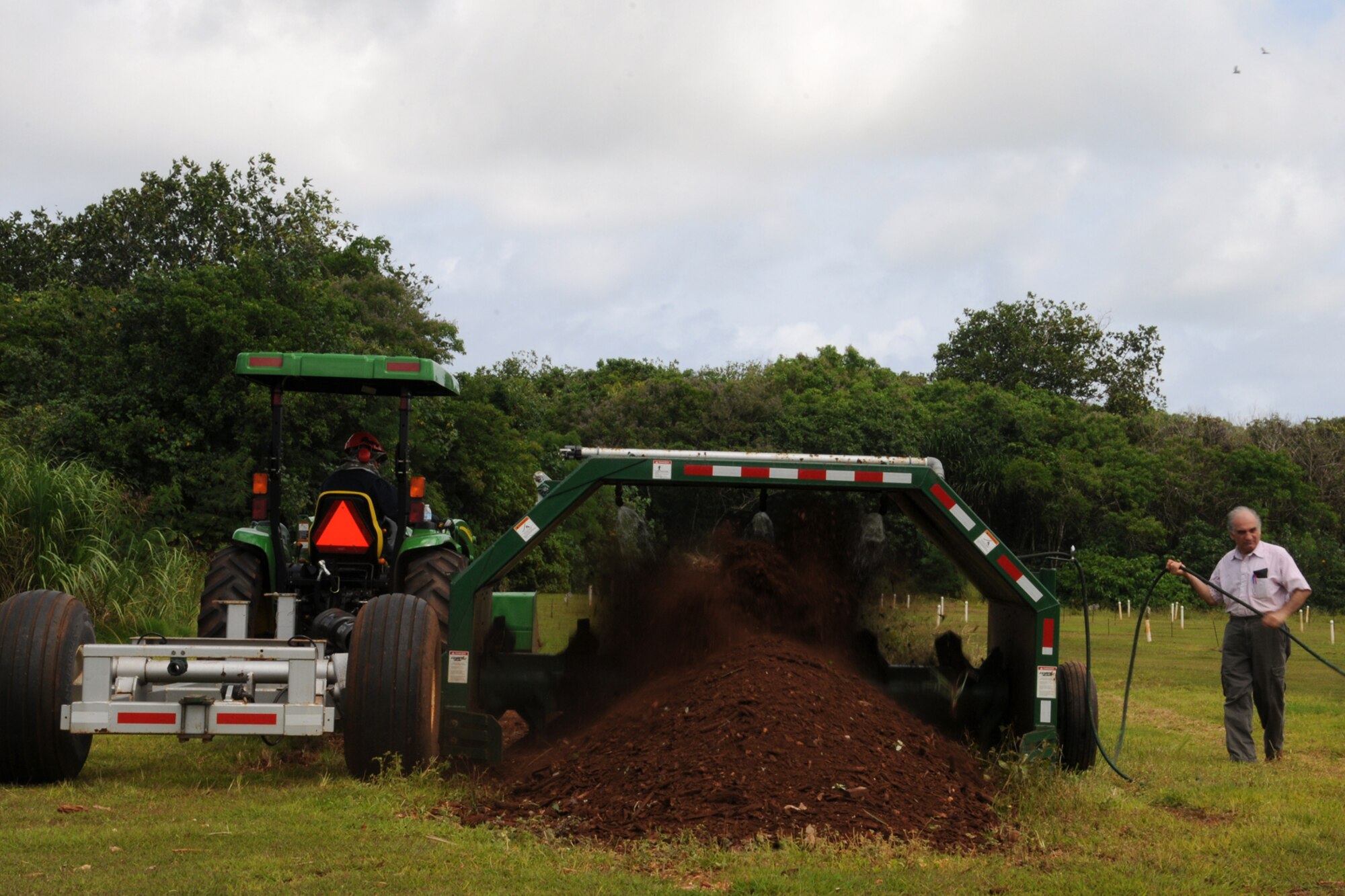 Mohammad Golabi, University of Guam associate professor of soil and environmental sciences, and a research technician turn compost June 19, 2013, at the UOG Research Farm in Yigo, Guam. The professor, technicians and students collected nearly 250 cubic yards of mulch from Andersen Air Force Base, Guam, throughout the year for a project that will benefit the local agriculture community. (U.S. Air Force photo by Staff Sgt. Melissa B.  White/Released)