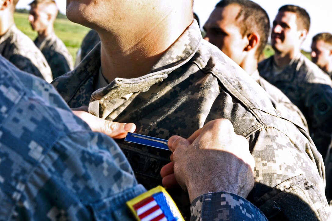 Army Col. Patrick Hynes, left, pins expert infantryman badges on candidates who completed testing on Fort Bragg, N.C., June 14, 2013. Hynes is commander of the 82nd Airborne Division's 2nd Brigade Combat Team. 