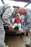 Maj. Eddie Brown and Staff Sgt. Timothy Gibson, Task Force Falcon, sat children one-by-one on the tailgate and fitted the children's feet for the perfect shoe.
