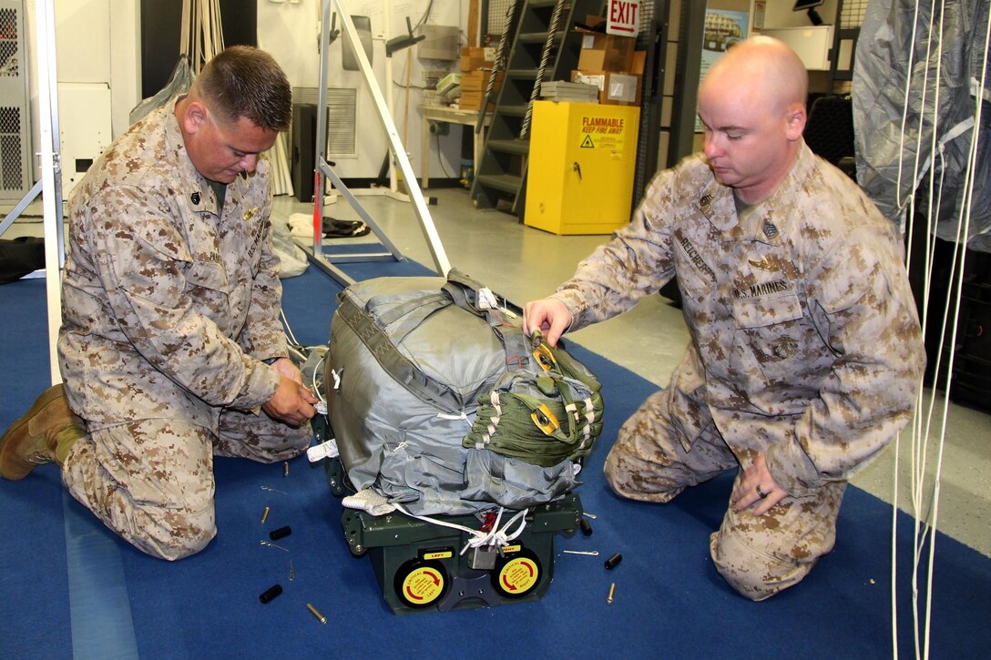 Staff Sgt. Stephen Parker (left) and Gunnery Sgt. Jacob Reichert prepare a JPADS 2K system. Once loaded aboard an aircraft, this system could drop up to 2,200 pounds of gear and supplies to Marines on the ground within 150 meters of its specified target.