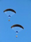 Two loaded JPADS 2K systems glide toward the ground on similar courses. Multiple JPADS with different impact points can be launched simultaneously from the same aircraft. 