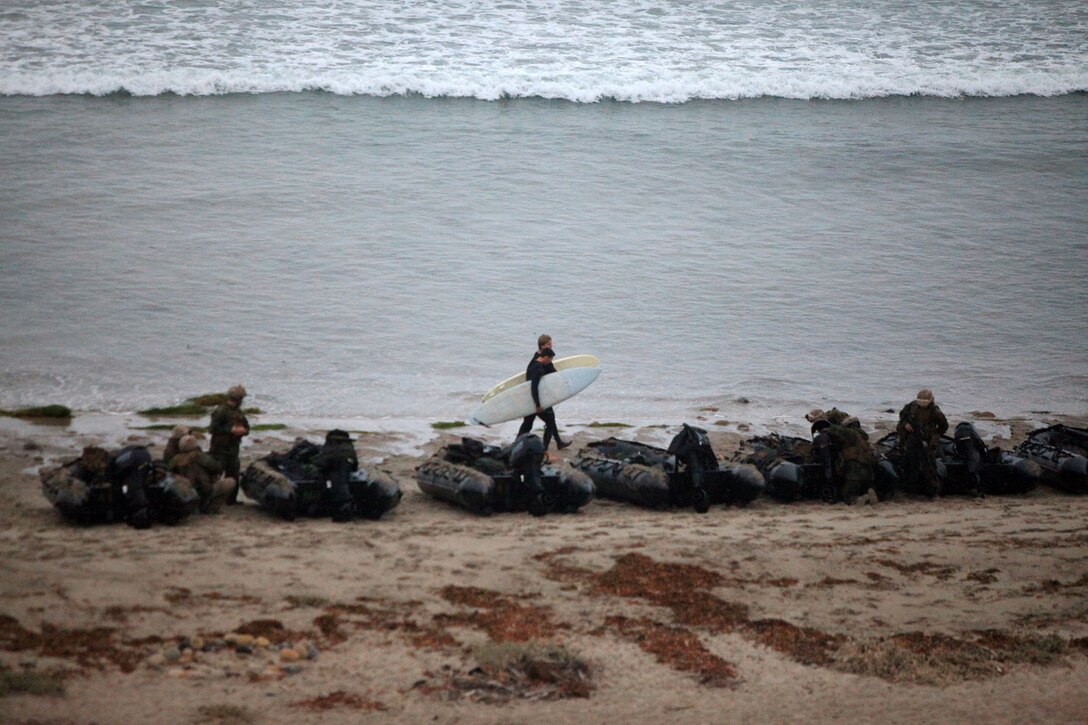 U.S. Marines with Battalion Landing Team 1/4, 13th Marine Expeditionary Unit, prepares to conduct an amphibious assault exercise during PHIBRON MEU Integration while surfers walk by at Green Beach, Calif., June 23, 2013. PMINT is a three week long pre-deployment training event focusing on the combined Marine Expeditionary Unit and Amphibious Ready Group capabilities and the strengthening of the Navy and Marine Corps team.