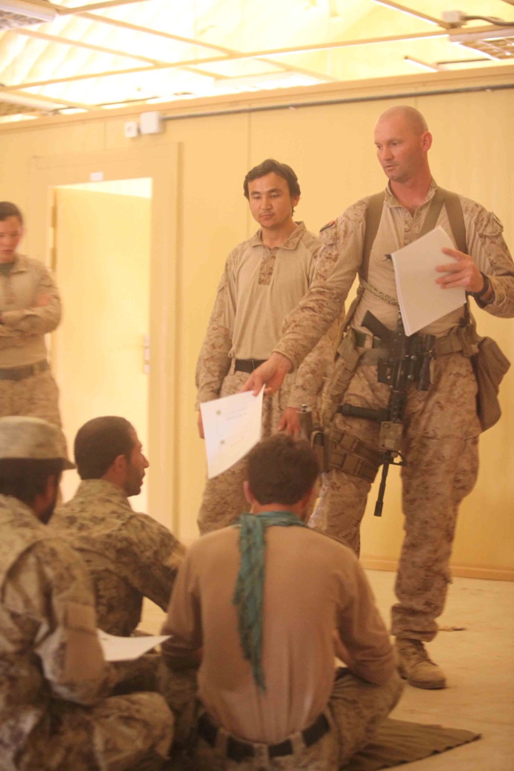 Garmser District, Afghanistan - Gunnery Sgt. Richard Fitzgerald, the senior enlisted advisor with Afghan National Civil Order Police Advisor Team 2, and a native of Mt. Pleasant, Mich., passes out study guides to ANCOP instructors at the station here, June 17, 2013. Fitzgerald gave out the study guides before class so Afghan police could follow along during the period of instruction. "We're trying to implement the training cycle phase so they understand the importance of the training prior to deploying to the next area," said Fitzgerald.