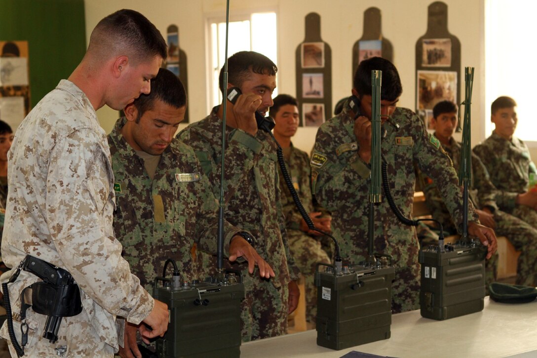 Corporal Bradley Mall, a radio operator with the Signals Kandak Advisor Team assists an Afghan National Army soldier during radio training here, June 17, 2013. Mall, a 22-year-old native of Hayden, Idaho, provided technical assistance during the hands-on portion of the training. The Marines with the Signals Kandak Advisor Team assist and advise the Afghan soldiers on radio operation, personal computer skills and electronics maintenance.