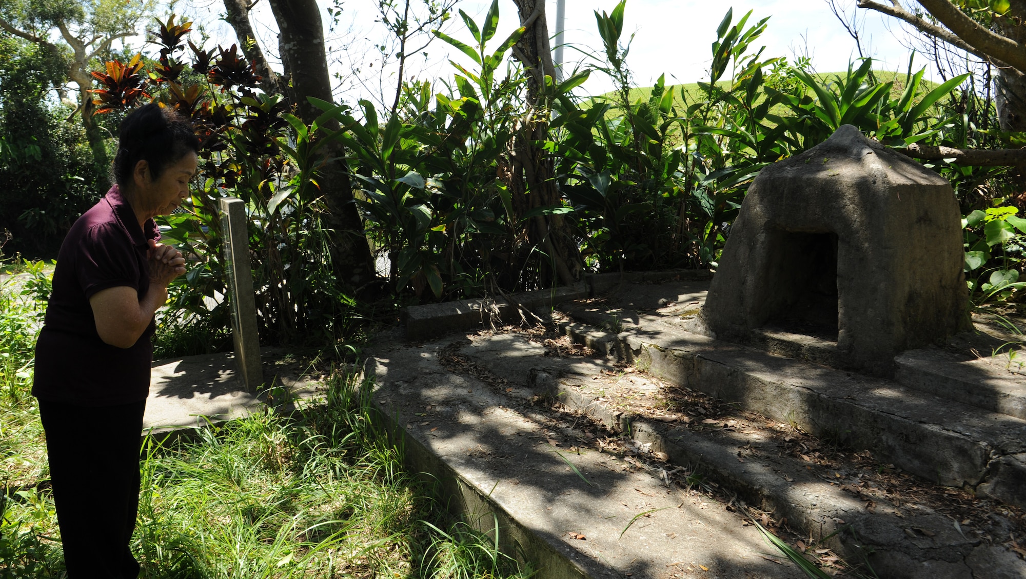 A local Japanese woman prays at a prayer monument during a sacred site tour on Kadena Air Base, Japan, June 22, 2013. The tour was conducted to allow local members, who used to live in the area before World War II, the opportunity to visit the land and share their culture and heritage with their family. (U.S. Air Force photo by Airman 1st Class Malia Jenkins/Released)