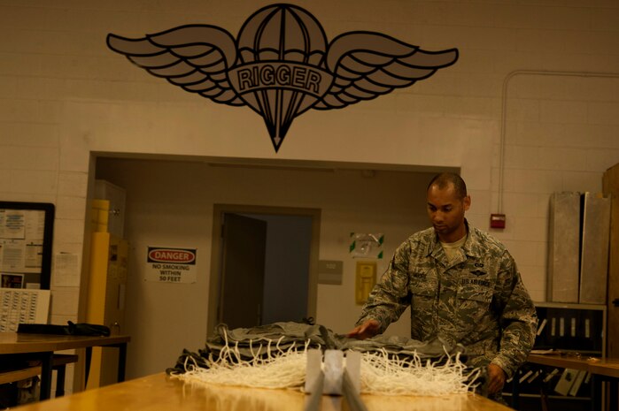 U.S. Air Force Staff Sgt. Shamir Moore, 58th Rescue Squadron aircrew flight equipment technician, wipes off a MC1-1D parachute before repacking it June 24, 2013, at Nellis Air Force Base, Nev. The MC1-1D parachute is used in low altitude static line jumps. (U.S. Air Force photo by Senior Airman Daniel Hughes)  