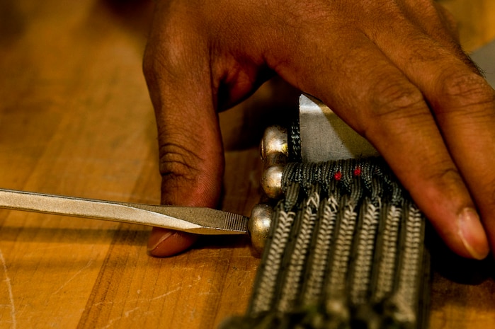U.S. Air Force Staff Sgt. Shamir Moore, 58th Rescue Squadron aircrew flight equipment technician, tightens a parachute cord before repacking a MC1-1D parachute June 24, 2013, at Nellis Air Force Base, Nev. During the repacking of a parachute the aircrew Airmen inspect the parachute to ensure there are no frayed cords or rips in the canopy. (U.S. Air Force photo by Senior Airman Daniel Hughes) 