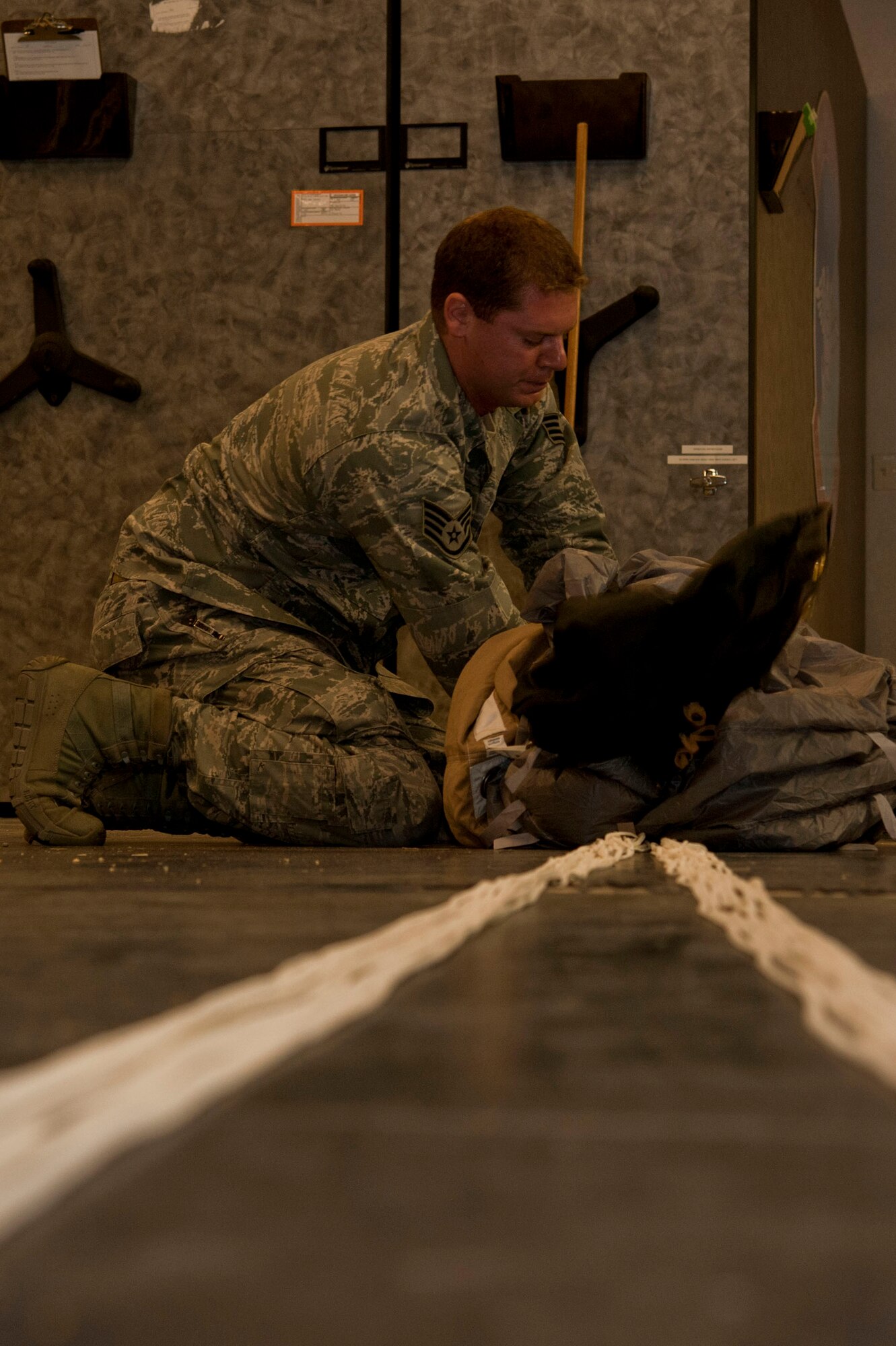 U.S. Air Force Staff Sgt. Kyle Burian, 58th Rescue Squadron aircrew flight equipment technician, folds a MC5 parachute June 24, 2013, at Nellis Air Force Base, Nev. Folding the parachute correctly ensures it fits correctly into the jumper’s backpack. (U.S. Air Force photo by Senior Airman Daniel Hughes) 