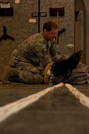 U.S. Air Force Staff Sgt. Kyle Burian, 58th Rescue Squadron aircrew flight equipment technician, folds a MC5 parachute June 24, 2013, at Nellis Air Force Base, Nev. Folding the parachute correctly ensures it fits correctly into the jumper’s backpack. (U.S. Air Force photo by Senior Airman Daniel Hughes) 