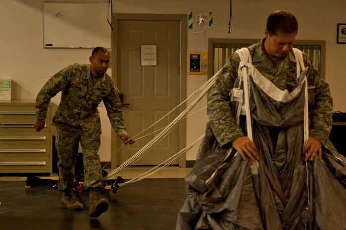 U.S. Air Force Staff Sgt. Shamir Moore, 58th Rescue Squadron aircrew flight equipment, inspects the lines as Staff Sgt. Kyle Burian repacks a MC5 parachute June 24, 2013, at Nellis Air Force Base, Nev. Inspecting the lines ensures they are not tangled, so when the canopy is deployed it can fully open. (U.S. Air Force photo by Senior Airman Daniel Hughes)